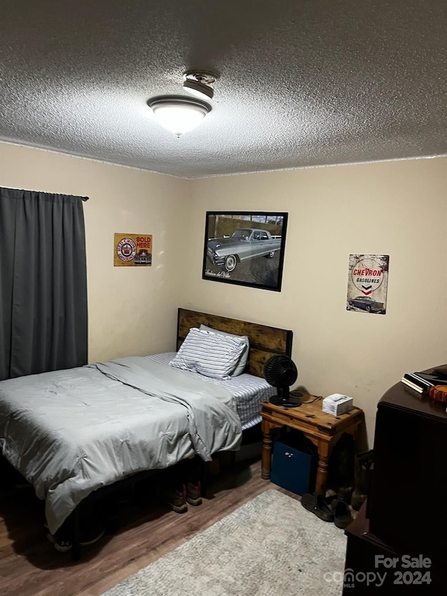 bedroom featuring hardwood / wood-style flooring and a textured ceiling