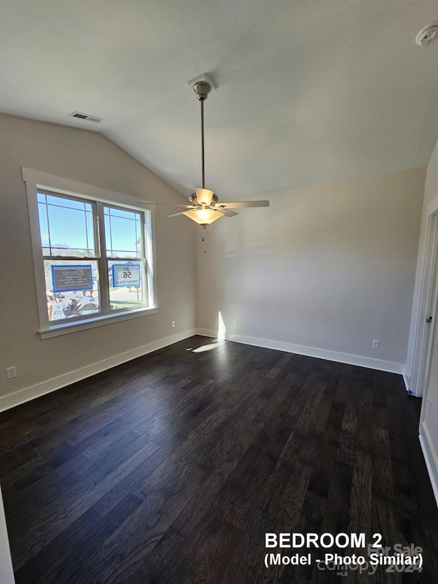 empty room featuring ceiling fan, dark hardwood / wood-style floors, and vaulted ceiling