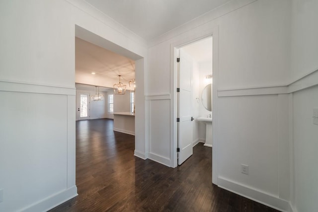 hall with a notable chandelier and dark hardwood / wood-style flooring