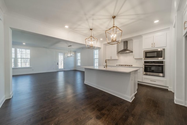 kitchen with wall chimney exhaust hood, an island with sink, dark wood-type flooring, and appliances with stainless steel finishes