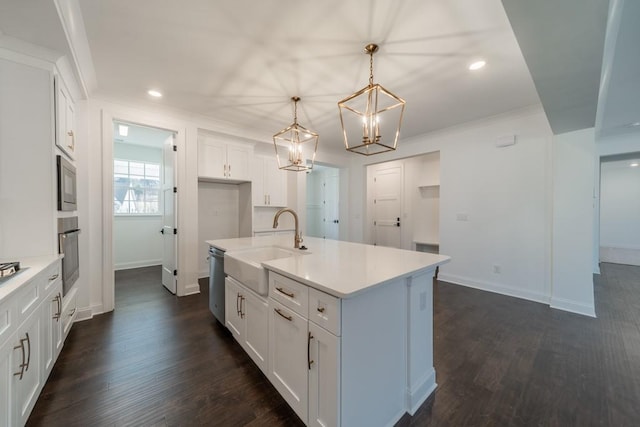 kitchen featuring decorative light fixtures, a center island with sink, white cabinetry, crown molding, and dark hardwood / wood-style floors