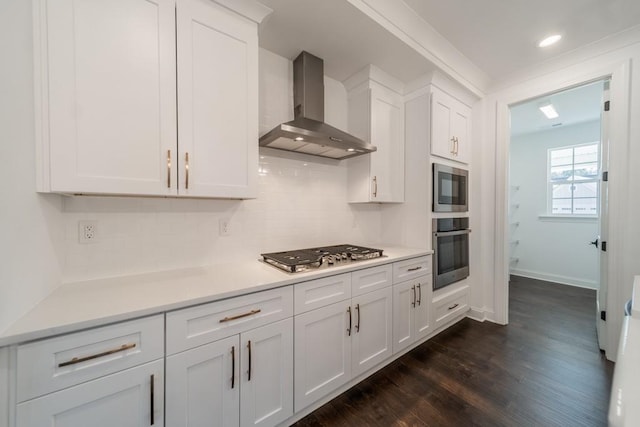 kitchen featuring dark hardwood / wood-style flooring, white cabinets, appliances with stainless steel finishes, backsplash, and wall chimney exhaust hood