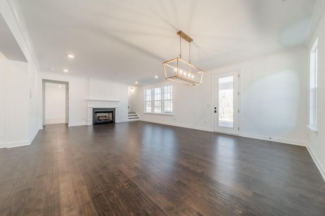 unfurnished living room featuring a notable chandelier and dark hardwood / wood-style floors