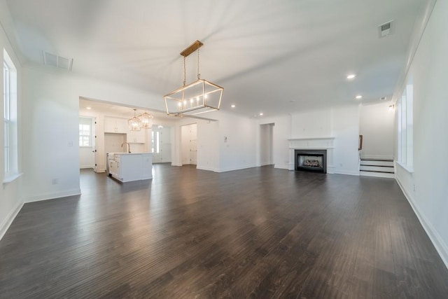 unfurnished living room featuring dark hardwood / wood-style flooring, sink, and a chandelier