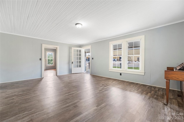 unfurnished living room with crown molding and dark wood-type flooring