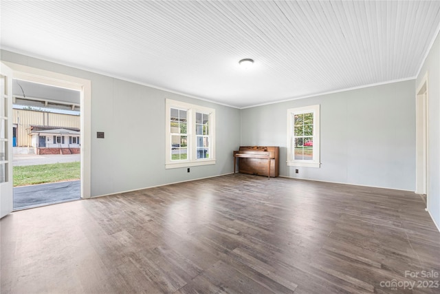 unfurnished living room featuring dark hardwood / wood-style flooring, crown molding, and plenty of natural light