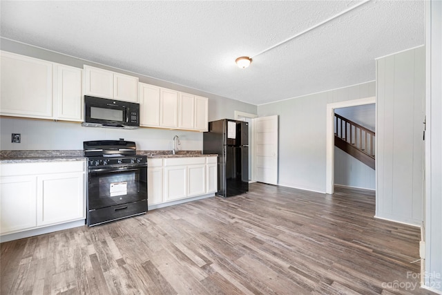 kitchen featuring sink, light hardwood / wood-style flooring, black appliances, a textured ceiling, and white cabinetry