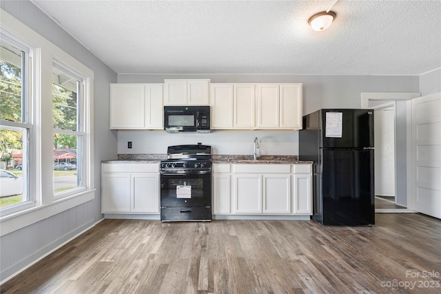 kitchen with white cabinets, light hardwood / wood-style floors, black appliances, and sink