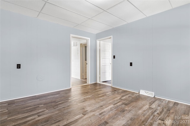 unfurnished room featuring a paneled ceiling and dark hardwood / wood-style floors