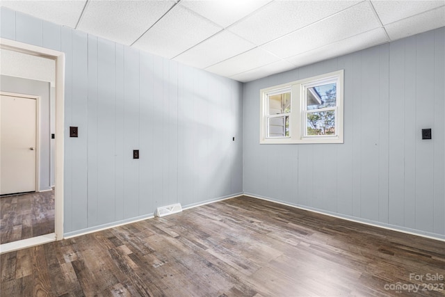 spare room with a paneled ceiling and dark hardwood / wood-style floors