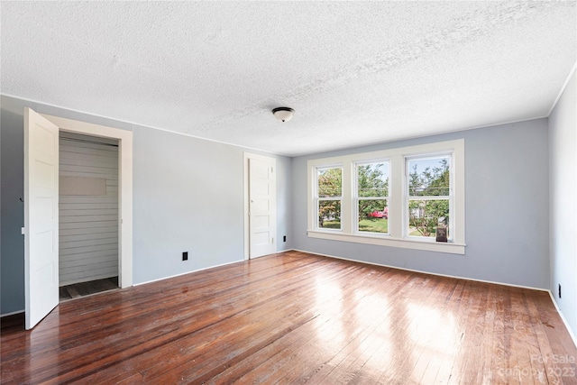 empty room with a textured ceiling and dark hardwood / wood-style floors