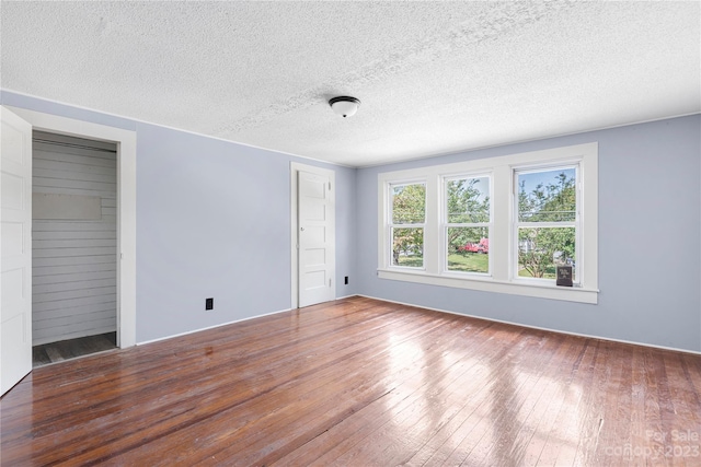 spare room with a textured ceiling and dark hardwood / wood-style flooring