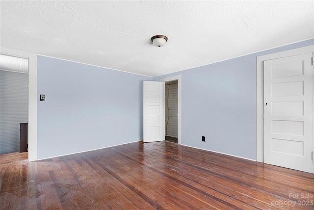 spare room featuring a textured ceiling and dark wood-type flooring