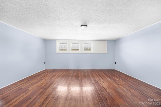 empty room featuring a textured ceiling and dark hardwood / wood-style flooring