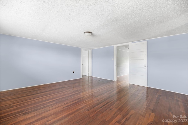 unfurnished room with dark hardwood / wood-style flooring and a textured ceiling