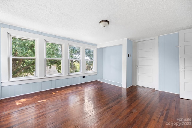 spare room with dark hardwood / wood-style floors and a textured ceiling