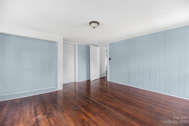 spare room with a textured ceiling and dark hardwood / wood-style flooring