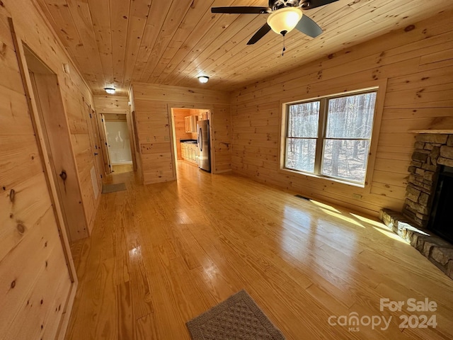 unfurnished living room with a fireplace, ceiling fan, wooden ceiling, and light hardwood / wood-style flooring