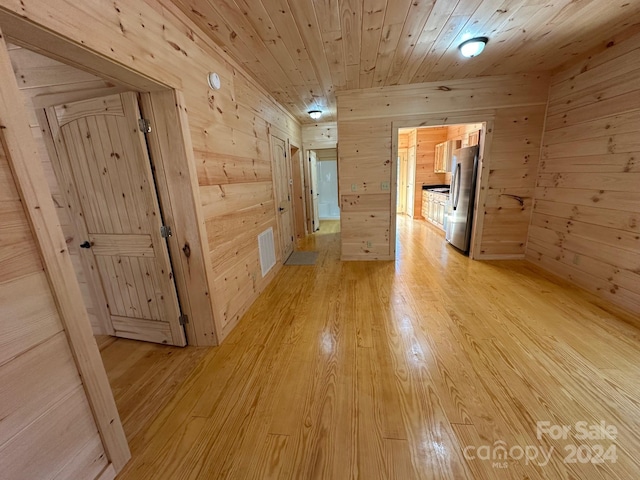 hall featuring wood walls, light hardwood / wood-style flooring, and wood ceiling