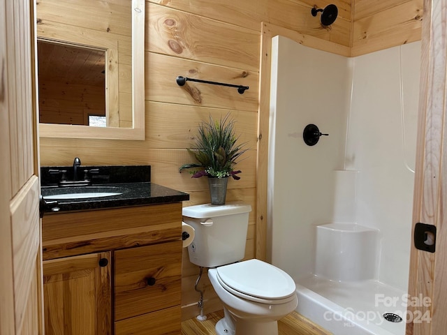 bathroom featuring wood walls, vanity, toilet, and walk in shower