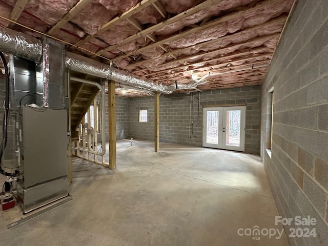 basement featuring french doors and heating utilities