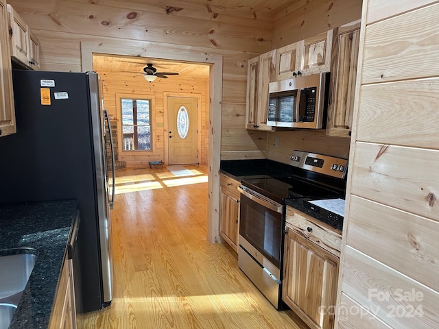 kitchen with stainless steel appliances, ceiling fan, wood ceiling, wooden walls, and light wood-type flooring