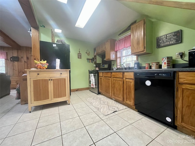 kitchen with wood walls, light tile floors, black dishwasher, stainless steel electric stove, and lofted ceiling with skylight