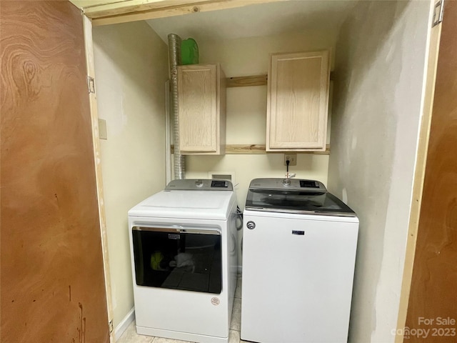 clothes washing area with washing machine and clothes dryer, cabinets, and light tile floors