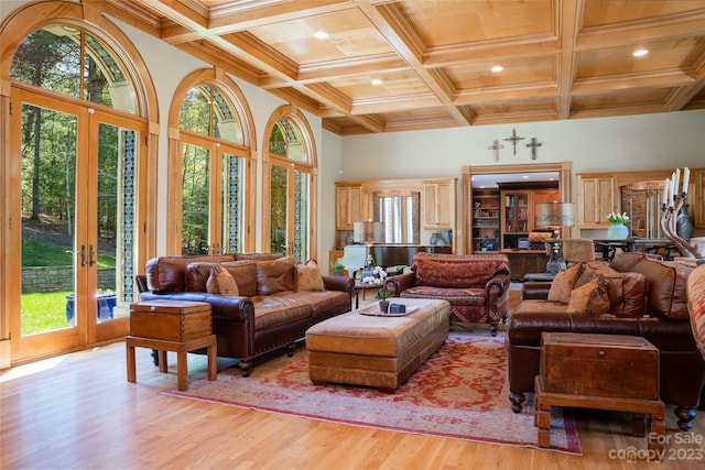 living room with beam ceiling, coffered ceiling, a wealth of natural light, and light wood-type flooring