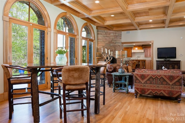 dining area featuring coffered ceiling, light hardwood / wood-style floors, and beamed ceiling