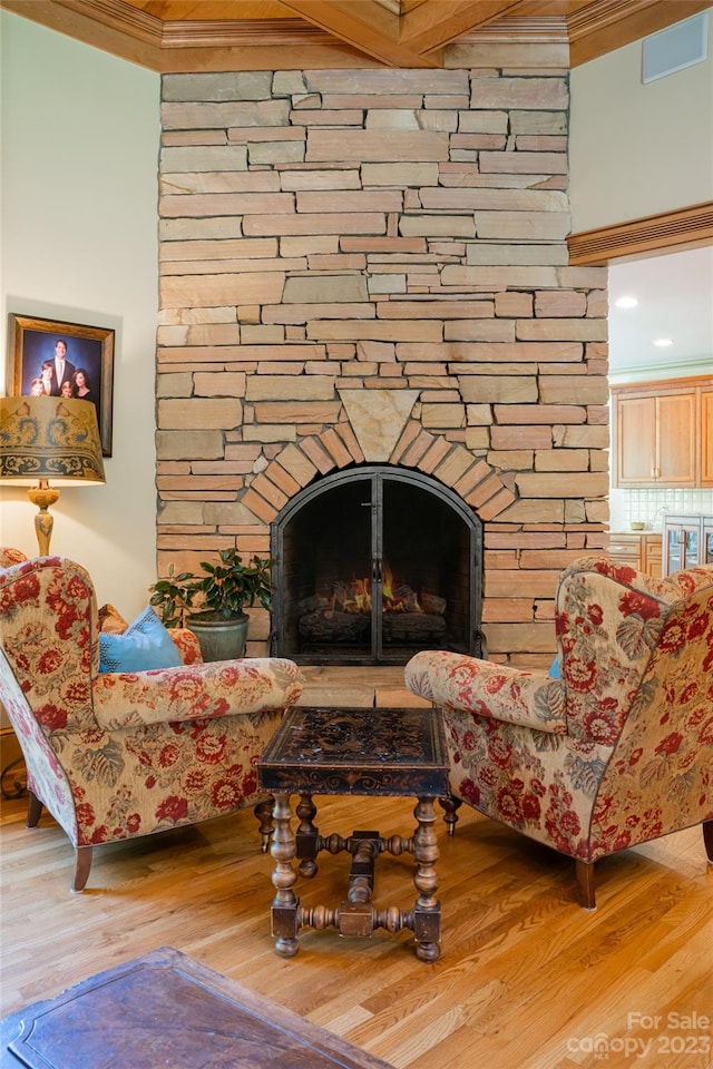 living area with ornamental molding, light hardwood / wood-style floors, and a fireplace