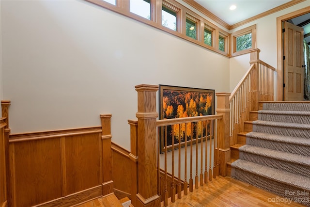 stairway with light hardwood / wood-style floors and ornamental molding