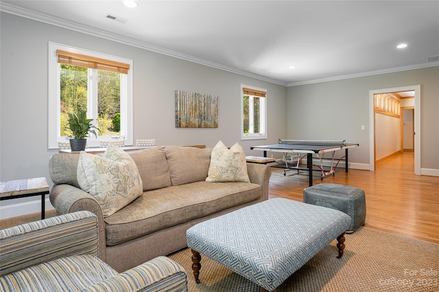 living room with light hardwood / wood-style flooring, ornamental molding, and a healthy amount of sunlight