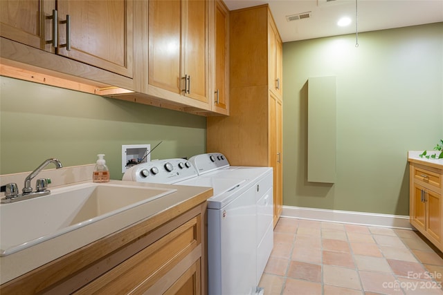 washroom featuring washing machine and dryer, light tile floors, cabinets, and sink