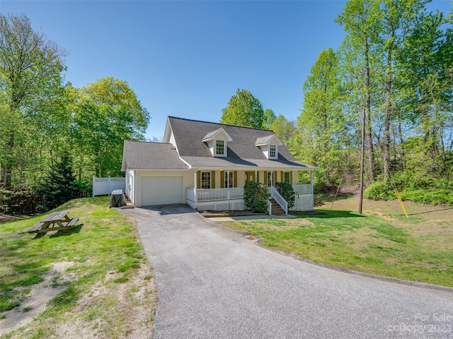 cape cod house with a porch, a front yard, and a garage