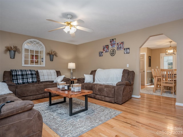 living room with light hardwood / wood-style flooring and ceiling fan with notable chandelier