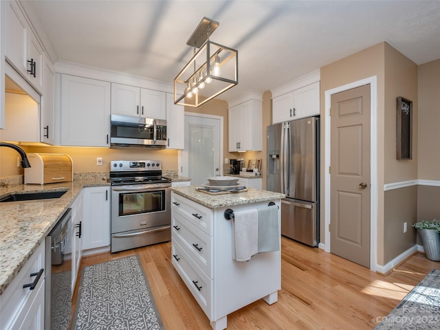 kitchen with sink, light hardwood / wood-style floors, stainless steel appliances, decorative light fixtures, and white cabinets