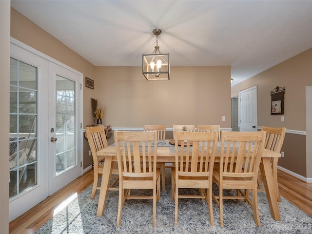 dining area with an inviting chandelier, french doors, and light hardwood / wood-style floors