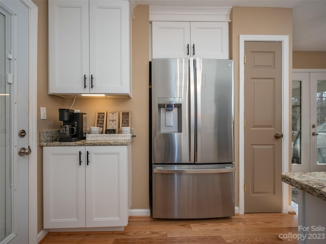 kitchen with white cabinetry, light stone countertops, light wood-type flooring, and stainless steel fridge with ice dispenser