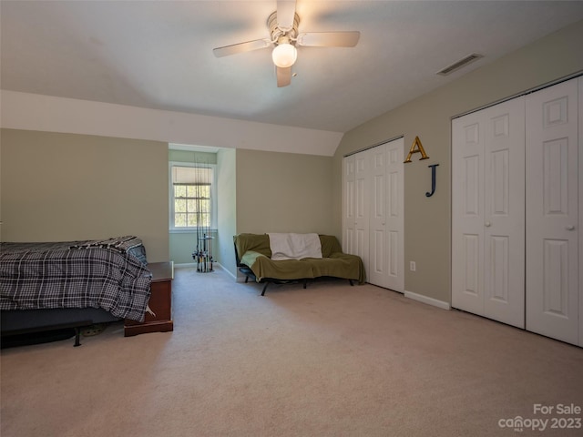 carpeted bedroom featuring ceiling fan, lofted ceiling, and two closets