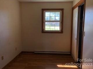 empty room with baseboard heating and dark hardwood / wood-style floors