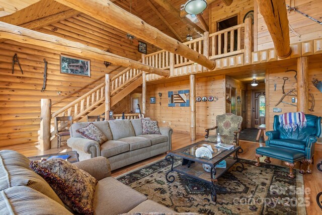 living room with rustic walls, high vaulted ceiling, wooden ceiling, beamed ceiling, and hardwood / wood-style floors