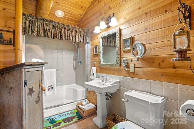 bathroom with toilet, vaulted ceiling, tile walls, a shower with door, and tile patterned flooring