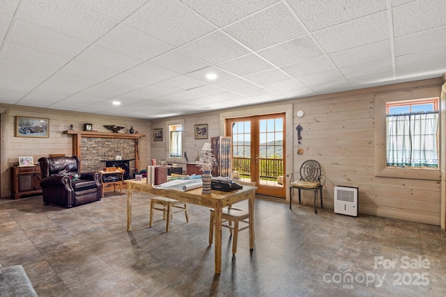 dining room featuring a fireplace, a healthy amount of sunlight, and wooden walls