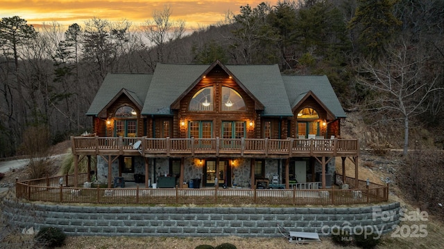 back house at dusk featuring a deck and a patio