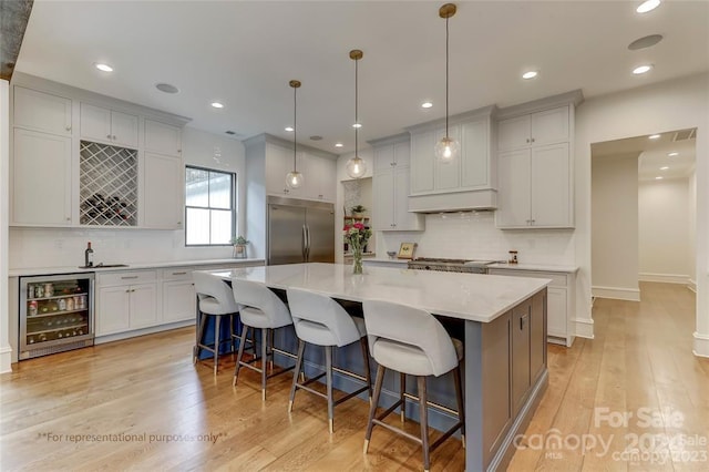 kitchen with wine cooler, a center island, stainless steel built in fridge, and light wood-type flooring