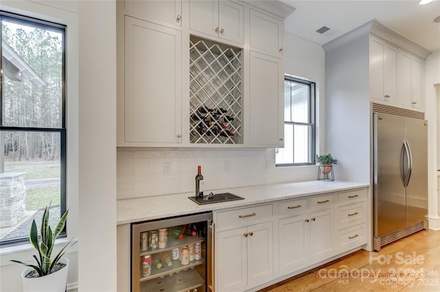 kitchen featuring light hardwood / wood-style floors, stainless steel built in refrigerator, white cabinets, wine cooler, and backsplash