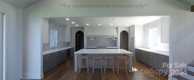 kitchen featuring hanging light fixtures, dark wood-type flooring, a center island, and tasteful backsplash