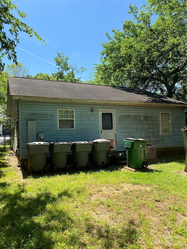 rear view of property featuring a lawn and central AC unit