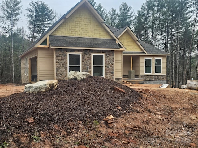 craftsman-style home featuring stone siding and a shingled roof